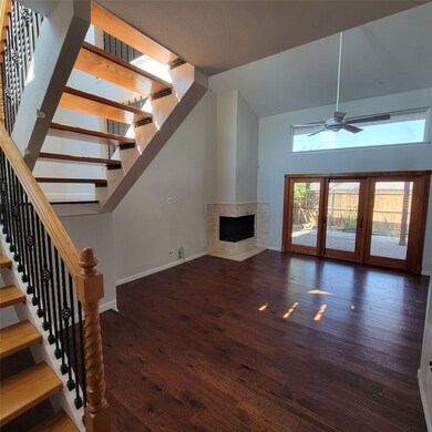 Living room with a high end fireplace, wood finished floors, stairs, a ceiling fan, and high vaulted ceiling with french doors to patio