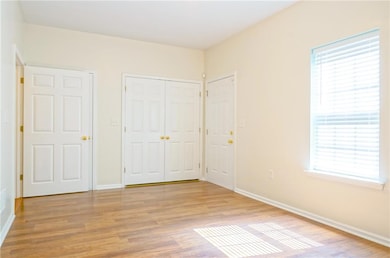 Unfurnished bedroom featuring baseboards, light wood-style floors, and a closet