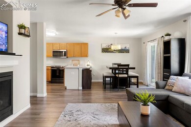 Living area featuring wood finished floors, a ceiling fan, and a fireplace