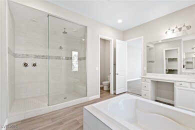 Bathroom with tiled shower, a bath, vanity, wood f