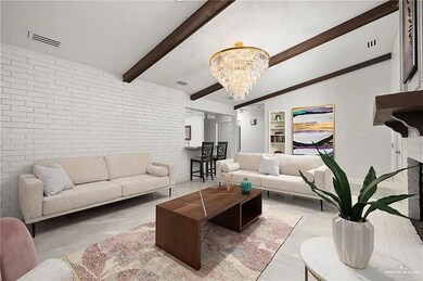 Living room featuring a chandelier, beam ceiling, and brick wall