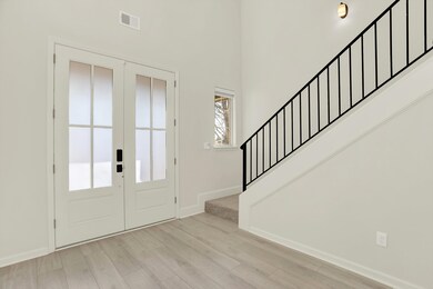Entrance foyer featuring french doors, a towering ceiling, and light hardwood / wood-style floors