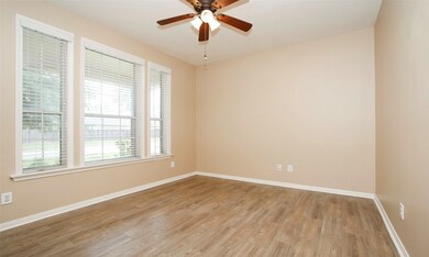Study overlooking covered front porch with wood look tile flooring, blinds, ceiling fan and lots of natural light.