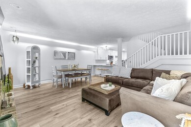 Living area with light wood-style flooring, arched walkways, stairway, and a textured ceiling