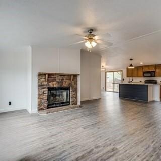 Unfurnished living room featuring a stone fireplac