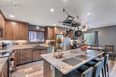 Kitchen featuring light stone countertops, light wood-type flooring, decorative backsplash, recessed lighting, and a textured ceiling