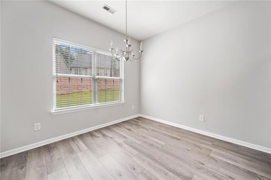 Spare room featuring a chandelier, wood finished floors, and baseboards