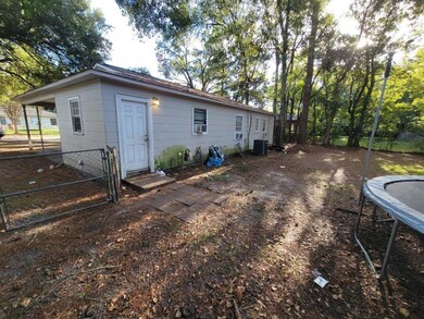 Back of house featuring a gate, a trampoline, and crawl space