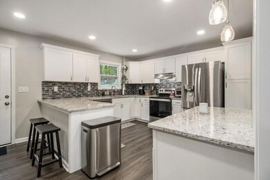 Updated Kitchen With Granite Counters, White Shaker Cabinets, Tiled Backsplash, & A Breakfast Bar