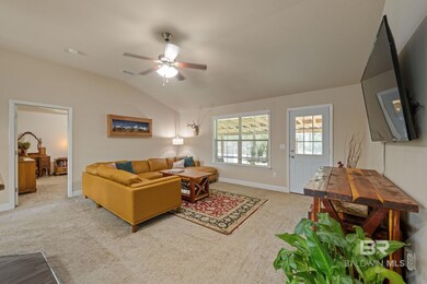 Carpeted living room featuring ceiling fan and vaulted ceiling