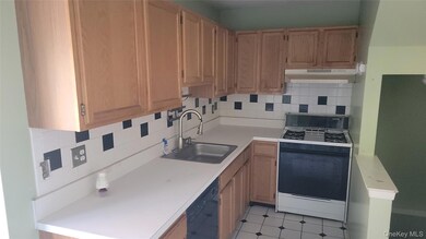 Kitchen featuring backsplash, gas range oven, light countertops, under cabinet range hood, and black dishwasher