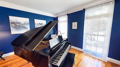 Flexible front room with hardwood floors and large windows. Ideal as a music room, office, or additional living space.