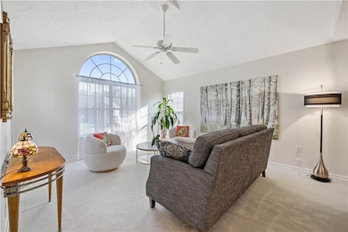 Living room boasts floor to ceiling Palladian window, wall to wall carpeting, ceiling fan.