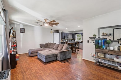 Living room featuring dark wood-type flooring, recessed lighting, and ceiling fan