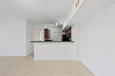 Kitchen featuring fridge, kitchen peninsula, a textured ceiling, and light tile patterned flooring