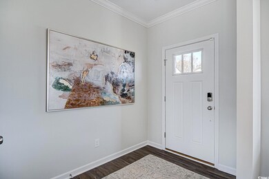 Entryway featuring dark wood-style floors, crown molding, and baseboards
