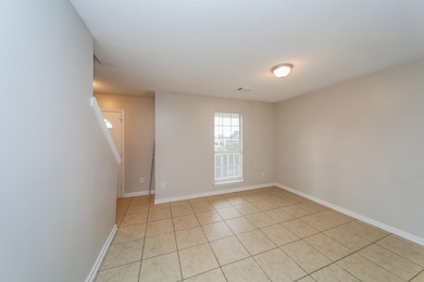 Empty room featuring light tile patterned floors and baseboards