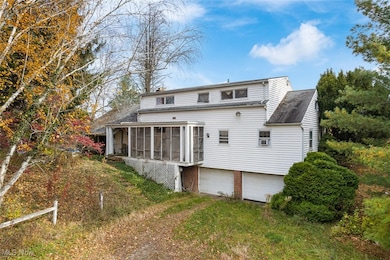 Rear view of property featuring a sunroom, an attached garage, and driveway