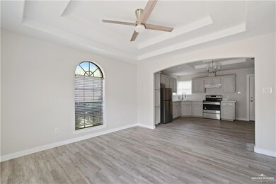 Unfurnished living room with a raised ceiling, light wood finished floors, and ceiling fan
