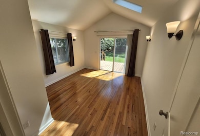 Unfurnished room with lofted ceiling, hardwood / wood-style flooring, a skylight, and healthy amount of natural light