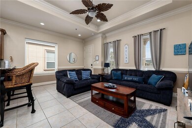 Living area featuring crown molding, light tile patterned floors, a ceiling fan, a raised ceiling, and recessed lighting