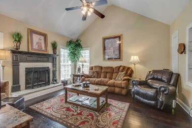 Great room features vaulted ceiling, gas fireplace and built in bookcase looking into dining room
