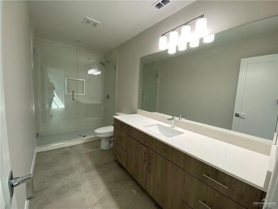 Bathroom with tile floors, a shower with door, vanity, and toilet