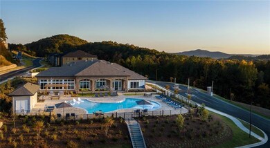 Pool at dusk with a community pool, a wooded view, and a patio area
