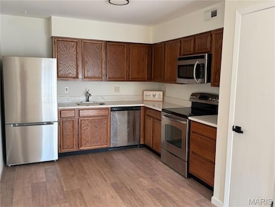 Kitchen featuring stainless steel appliances, light countertops, and light wood-type flooring