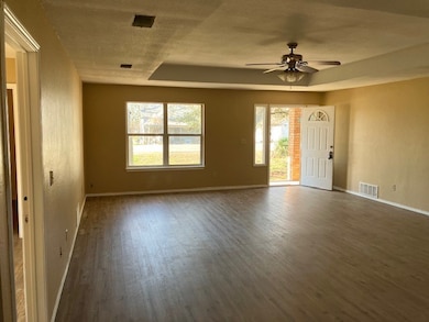 Empty room featuring a tray ceiling, wood finished floors, and ceiling fan
