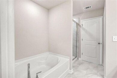 Bathroom featuring marble finish flooring, a garden tub, and a stall shower