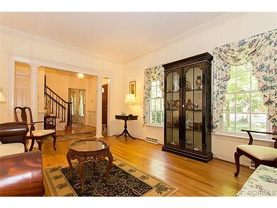 Columned living room with crown molding and hardwo