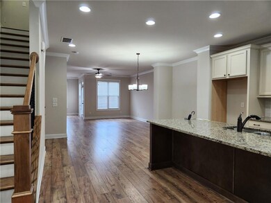 Kitchen featuring light stone counters, dark wood-type flooring, white cabinets, ceiling fan, and ornamental molding