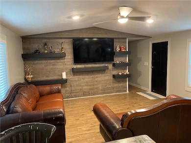 Living area with vaulted ceiling, light wood-style floors, and ceiling fan