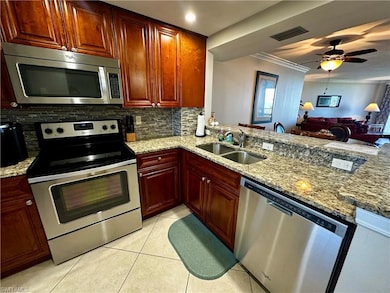 Kitchen featuring stainless steel appliances, light stone counters, tasteful backsplash, light tile patterned floors, and crown molding