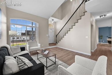 Living room featuring stairs, wood finished floors, and high vaulted ceiling