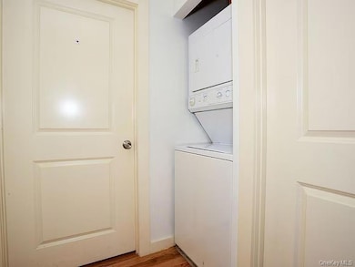 Laundry area with estacked washer and dryer and dark wood-style floors