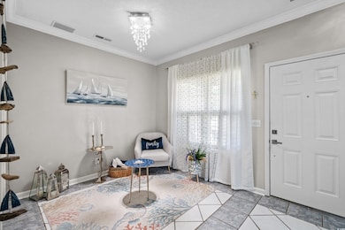 Living area with ornamental molding, baseboards, and light tile patterned flooring