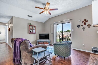 Living room with a textured ceiling, ceiling fan, dark wood-type flooring, and vaulted ceiling