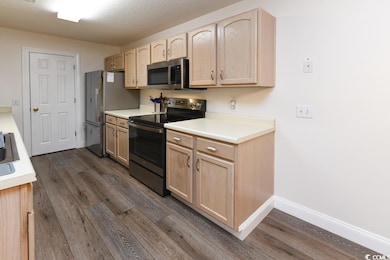 Kitchen featuring light brown cabinetry, appliance