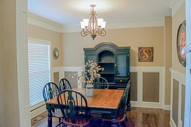 Separate Dining Room with Hardwood Flooring, Wainscoting, and Crown Molding