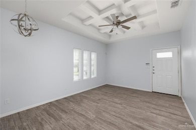 Unfurnished room with coffered ceiling, beamed ceiling, wood finished floors, a ceiling fan, and a chandelier