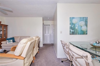 Living area with carpet flooring, ceiling fan, and baseboards