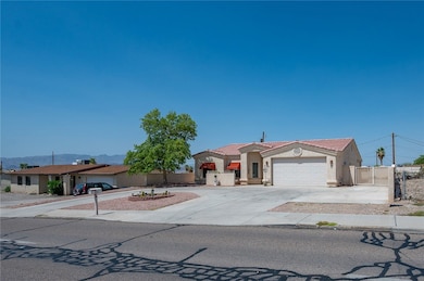 View of front facade featuring stucco siding, a garage, driveway, a gate, and a tile roof