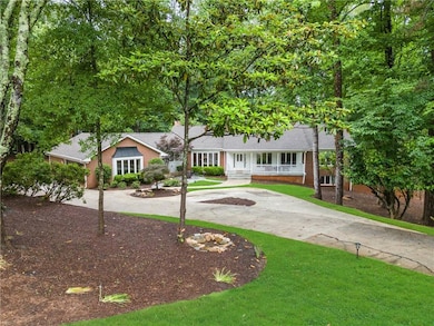 View of front of home featuring curved driveway, brick siding, a porch, and a front lawn
