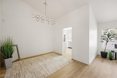 Unfurnished dining area featuring light wood-type flooring, a chandelier, and high vaulted ceiling