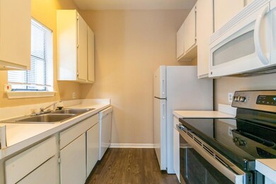 Kitchen featuring white appliances, dark wood finished floors, light countertops, and white cabinetry