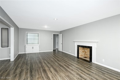 Unfurnished living room with dark wood-type flooring, a tile fireplace, and recessed lighting