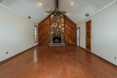 Unfurnished living room with a stone fireplace, wo