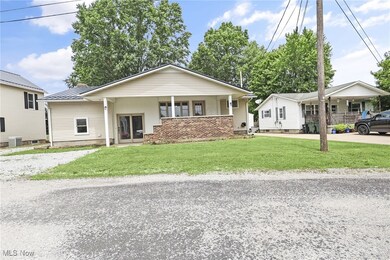 View of front of property featuring concrete driveway, a front lawn, a metal roof, and a porch